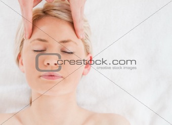 Young blond-haired woman getting a massage on her face