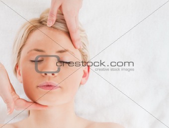 Beautiful blond-haired woman getting a massage on her face