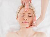Attractive blond-haired woman getting a massage on her face