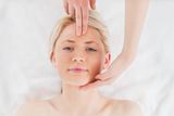 Cute blond-haired woman getting a massage on her face