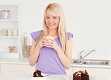 Smiling blonde woman eating cake and drinking coffee
