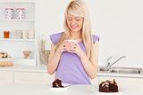 Attractive blonde woman eating cake and drinking coffee
