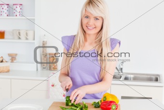 Beautiful blonde woman cutting vegetables in modern kitchen inte