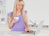 Beautiful woman holding a cup of coffee and relaxing on a laptop