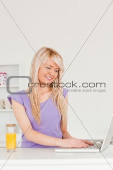 Beautiful woman relaxing on a laptop in the kitchen