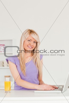 Beautiful female relaxing on a laptop in the kitchen