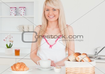Smiling blonde woman having her breakfast in the kitchen