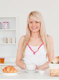 Smiling blonde female having her breakfast in the kitchen