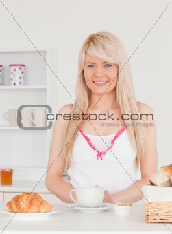Smiling blonde female having her breakfast in the kitchen