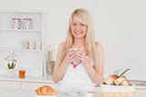 Attractive blonde woman having her breakfast in the kitchen