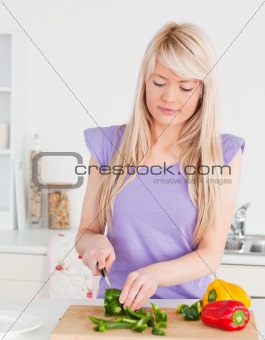 Gorgeous blonde woman cutting vegetables in modern kitchen inter
