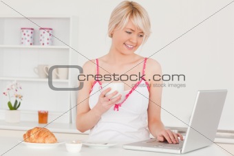 Attractive female having her breakfast while relaxing with a lap