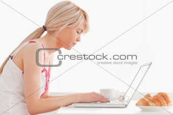 Beautiful female having her breakfast while working on a laptop