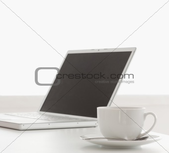 Modern laptop and cup of tea on a table