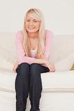 Attractive blonde female posing while sitting on a sofa