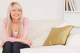 Good looking blonde woman posing while sitting on a sofa