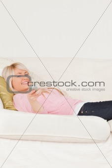 Good looking blonde female posing while lying on a sofa