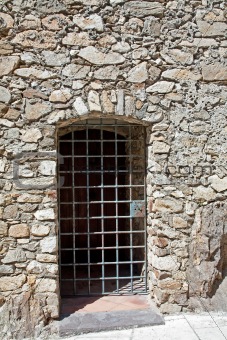 door made of bars in the old stone wall