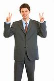 Pleased young businessman showing victory gesture
