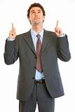 Interested modern businessman pointing finger up at copy space