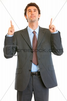 Interested modern businessman pointing finger up at copy space
