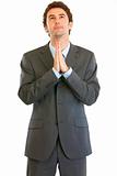 Young businessman with closed eyes praying for success
