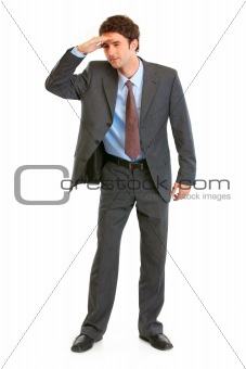 Concentrated young  businessman holding  his hand at forehead and looking forward in future
