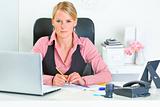 Authoritative business woman sitting at office desk
