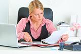 Concentrated business woman sitting at office desk and working with financial documents

