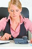 Concentrated business woman sitting at office desk and expecting phone call
