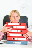 Work is done! Smiling business woman sitting at office desk with pile of folders 
