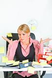 Shocked by set of tasks business woman sitting at workplace covered with sticky notes 
