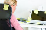 Business woman sitting at workplace covered with sticky notes 
