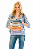 Smiling teen girl with pile of schoolbooks in hands reading
