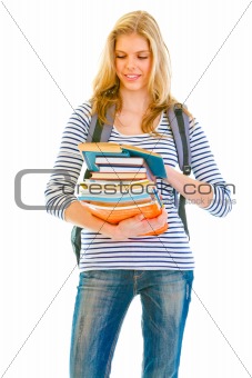 Smiling teen girl with pile of schoolbooks in hands reading
