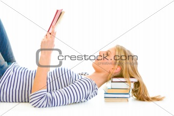 Lying on floor teengirl with resting head on pile of schoolbooks reading
