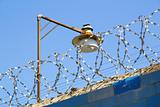 Barbed wire and lamp against the blue sky
