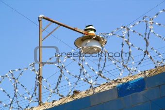 Barbed wire and lamp against the blue sky