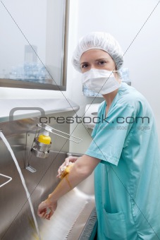 Medical woman in mask washing hands