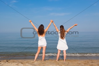 Two Young Women with Arms Outstretched on Seaside