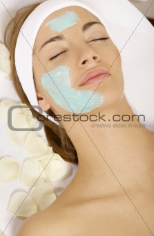young woman getting beauty skin mask treatment on her face with 