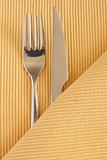 Metal fork and a knife lying on a yellow tablecloth