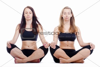 two young women sitting on the floor exercising yoga - isolated on white