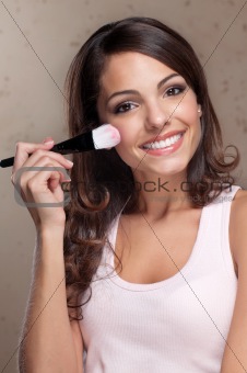 Pretty young woman applying blusher