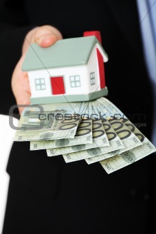 Businessman with money and house's model.
