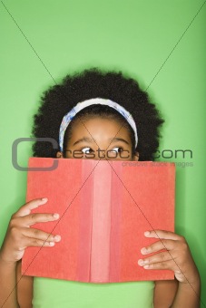Girl peeking over book.