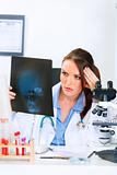 Concentrated doctor woman sitting at office table and analyzing patients roentgen
