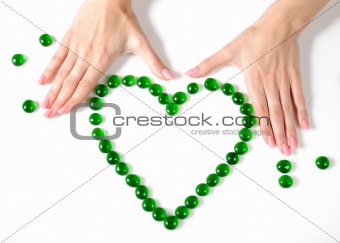 Beautiful hands building a heart sighn from green stones