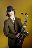 portrait of young funny man in bowler hat holding saxophone.