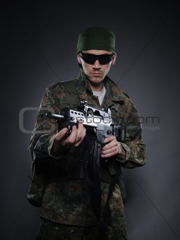 Young soldier in camouflage and ammunition with a gun